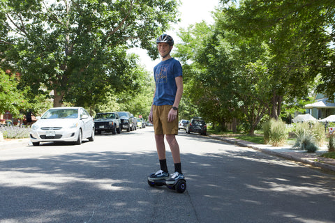 Teen riding a GOTRAX Black Edge LED Hoverboard for Kids down the road