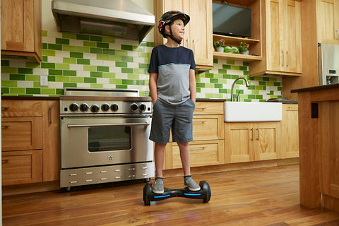 Child riding a GOTRAX Black Flash LED Hoverboard for Kids in a house