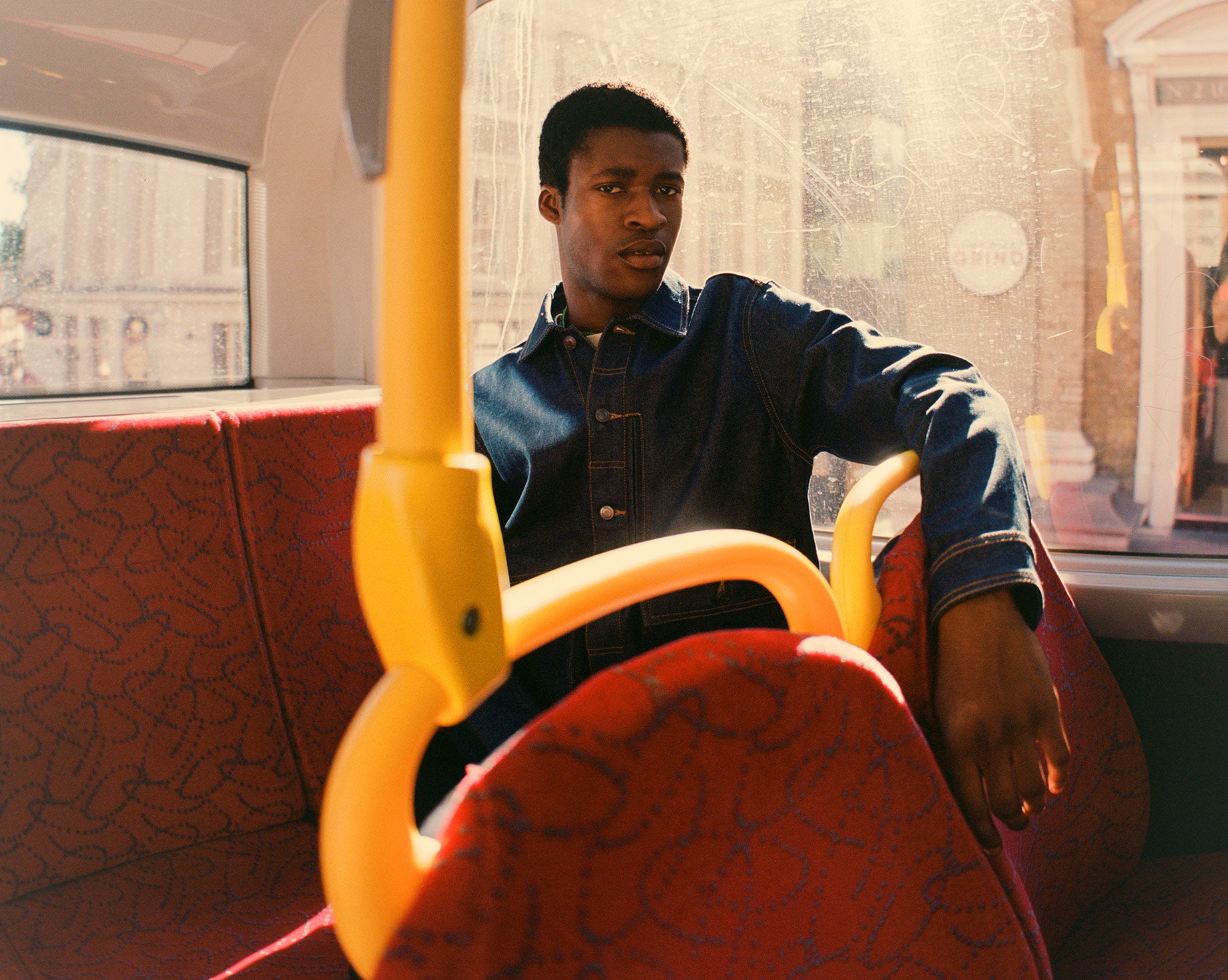 Model wears AW22 denim trucker jacket on London bus