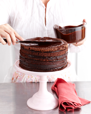 woman putting icing on cake with frosting knife