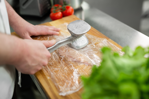 hand smashing meat with meat hammer