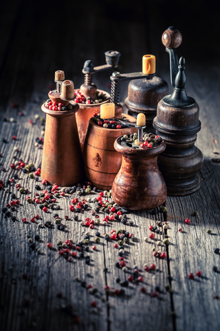 pepper grinder displayed with peppercorns scattered