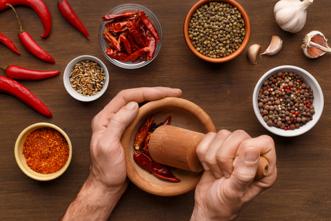man grinding chilies in mortar and pestle