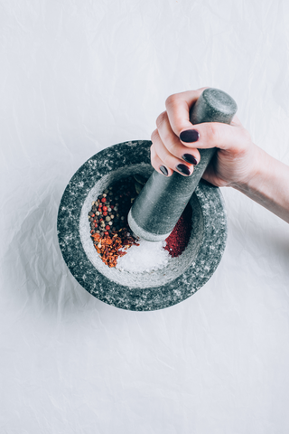woman grinding spices in a granite mortal and pestle