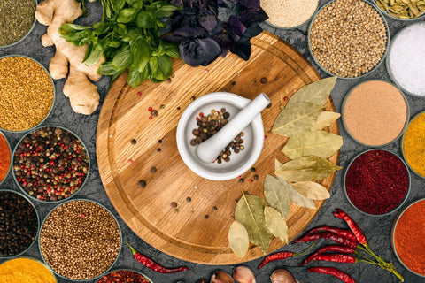 different types of spices displayed with a mortar and pestle