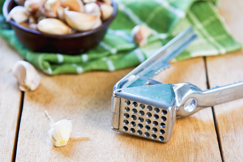 garlic press with pods of garlic around