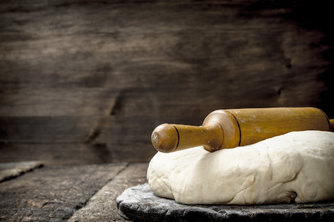 A rolling pin on some fresh dough