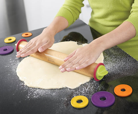 A lady wearing a green top and rolling out the dough with a Joseph Joseph rolling pin