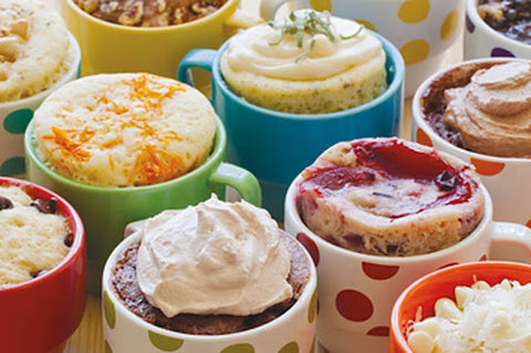 A variety of different mug cakes with different toppings on them 