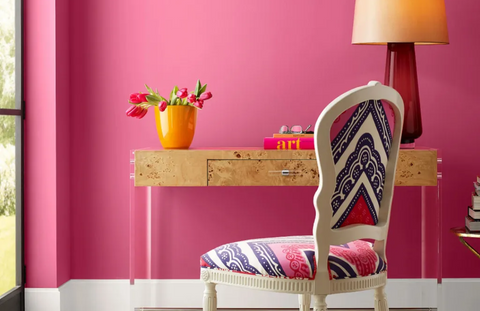 brightly painted pink room with a simple chic desk and colorful chair next to window