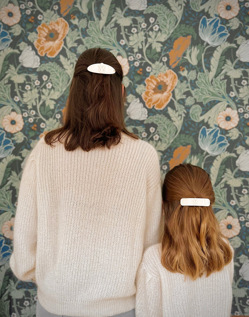 Mother and daughter wearing matching cardigans and matching hair clips