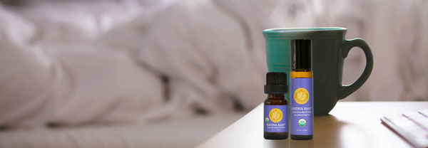 restful ease roll-on and undiluted bottle sitting on bedside table next to steaming coffee cup