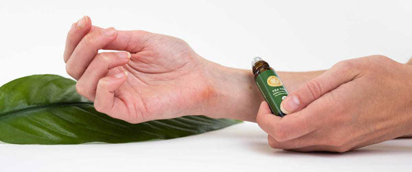 applying tea tree essential oil roll-on to arm