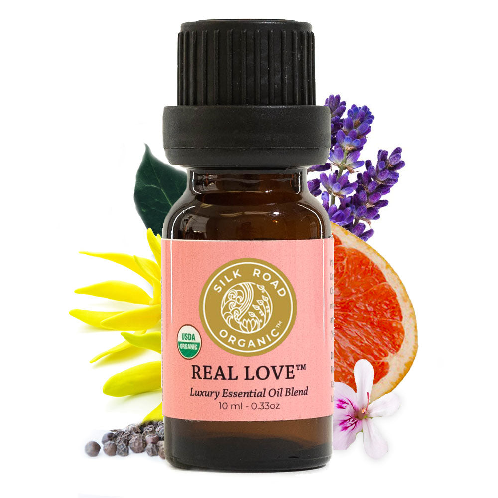 red silk essentials real love blend bottle with botanicals it contains behind it: geranium, pink grapefruit, ylang ylang, black pepper, copaiba balsam and lavender