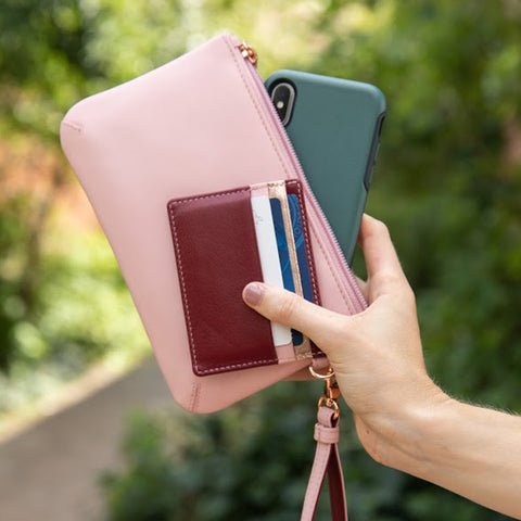 Una mujer sosteniendo un pequeño bolso de mano y una billetera.