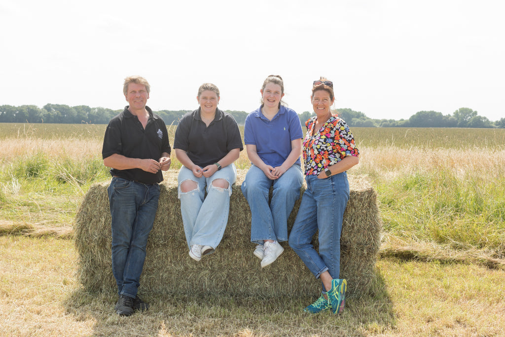 The Burrows family sitting on hay bale on the farm