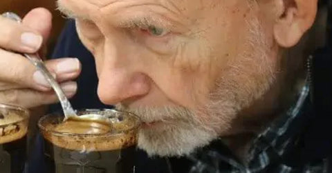 a senior citizen trying to taste a latte