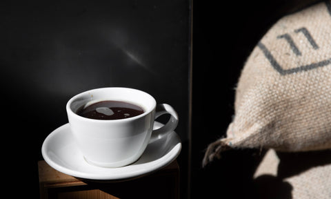 Acme coffee cup next to coffee bag at roastery.