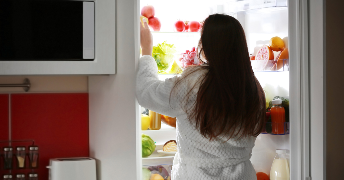 Woman looking through a refrigerator for high-protein snacks to satisfy cravings
