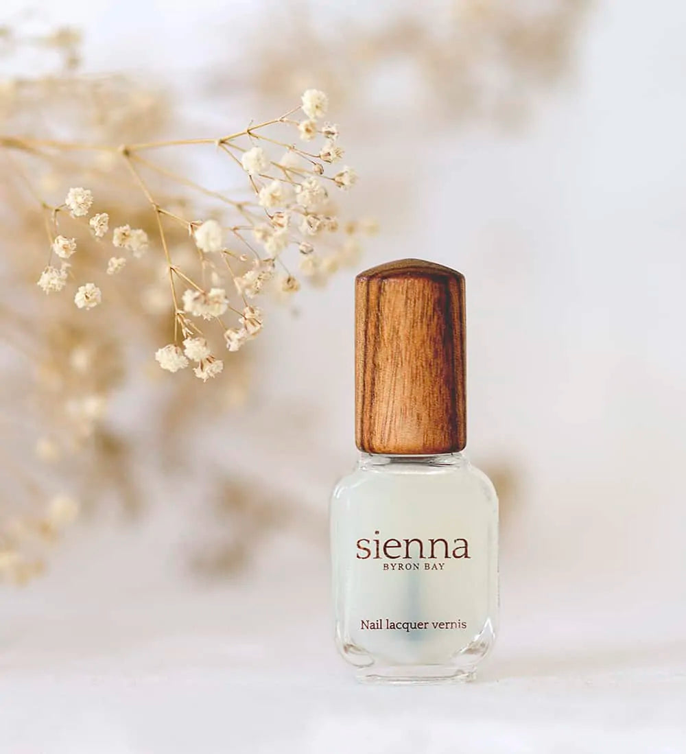 base coat nail polish glass bottle with timber cap by sienna on baby's breath flower background