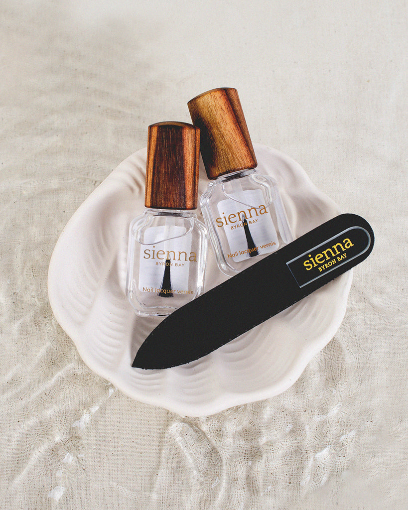 Care gift set, base and top coat with mini glass file on shell plate with water background