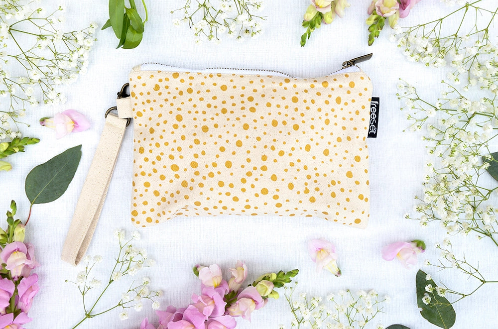 top shot of a 100% cotton beige pouch bag with gold dots by freeset global and kukukachu with flowers all around it
