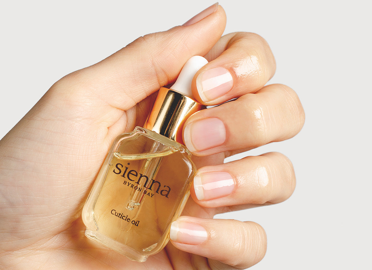 Fair skin hand holding cuticle oil bottle