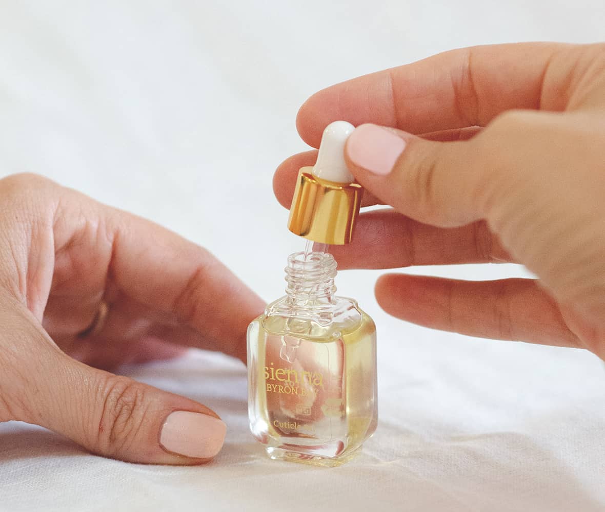 hands holding gold glass dropper from Sienna's cuticle oil bottle