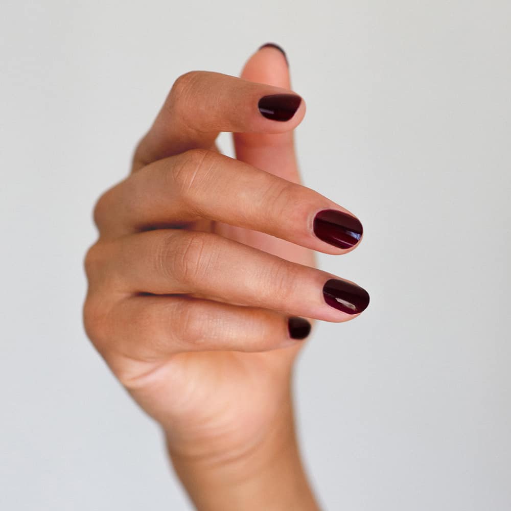 deep red plum nail polish hand swatch on medium skin tone by sienna