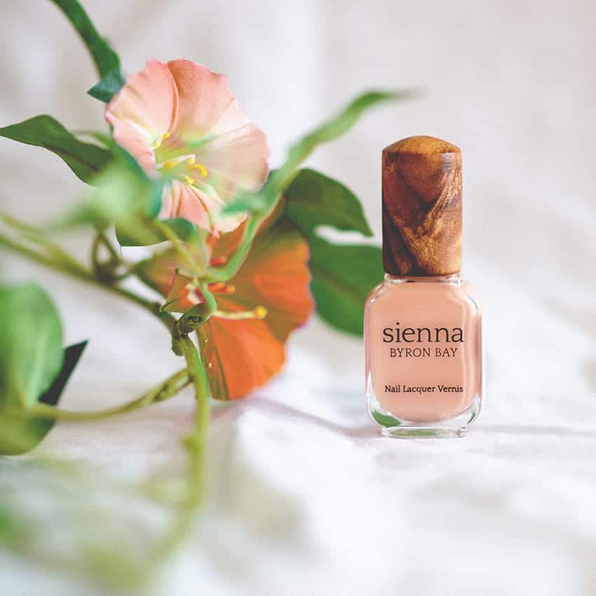 nude pink nail polish glass bottle with timber cap by sienna with orange flowers