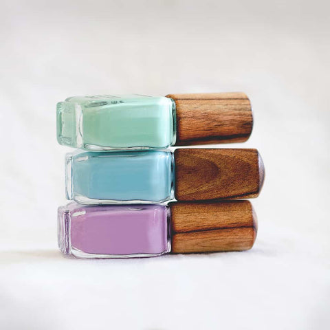 stack of three green blue and purple nail polish glass bottle with timber cap by sienna