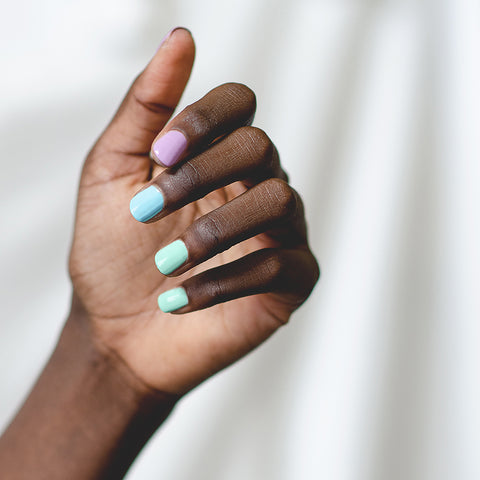 Hand swatch of pastel purple green blue ombre nails on dark skin tone by sienna