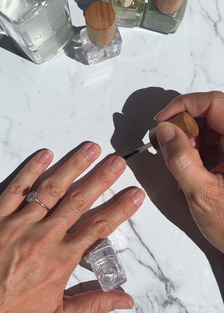 Fair skin hand applying Base Coat onto nails by Sienna Byron Bay.