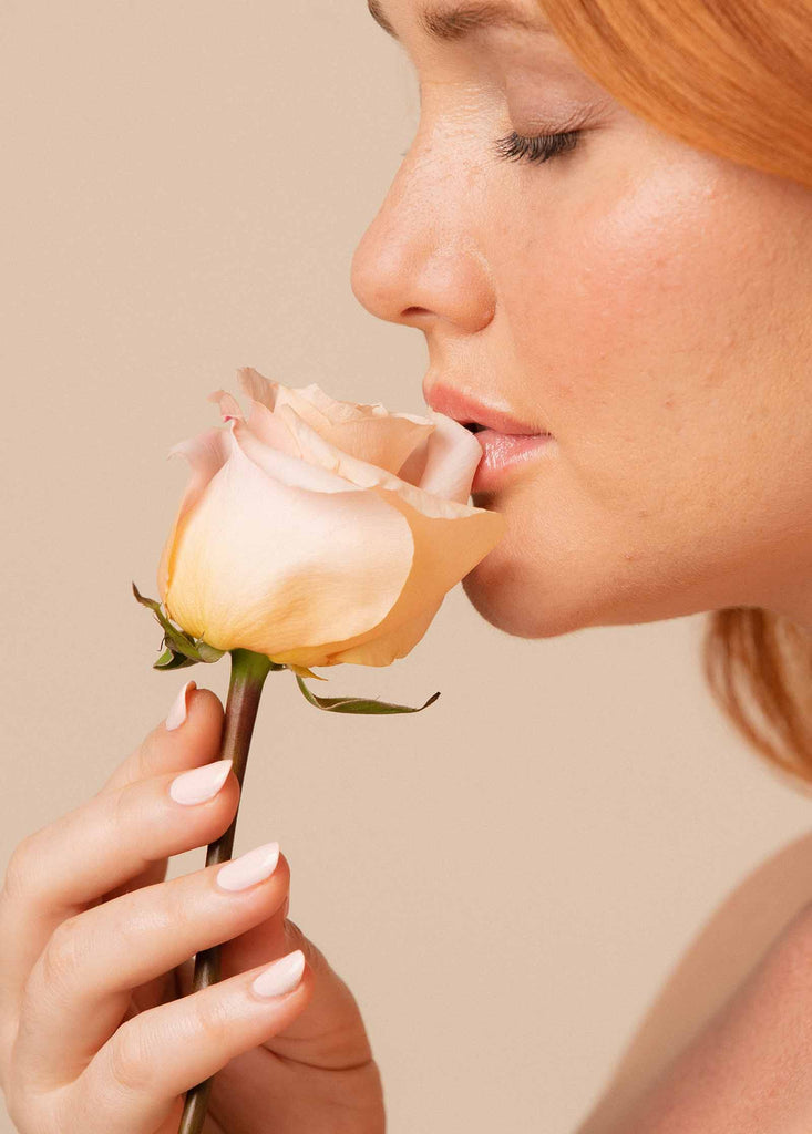 Woman with fair skin smelling rose wearing Melody nail polish by SIenna