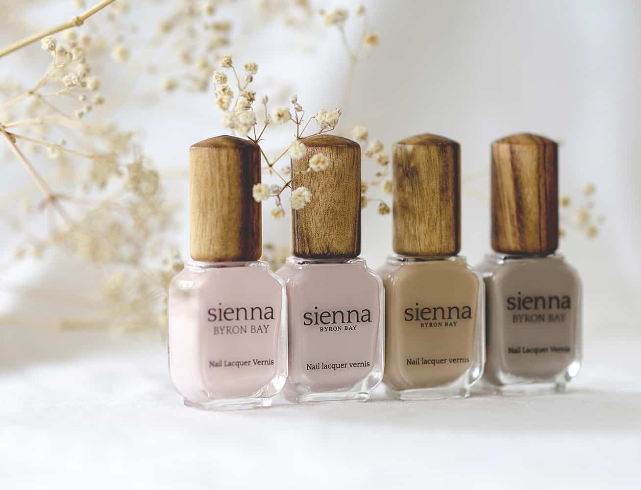 neutral nail polish glass bottle with timber cap by sienna and baby's breath flower in the background