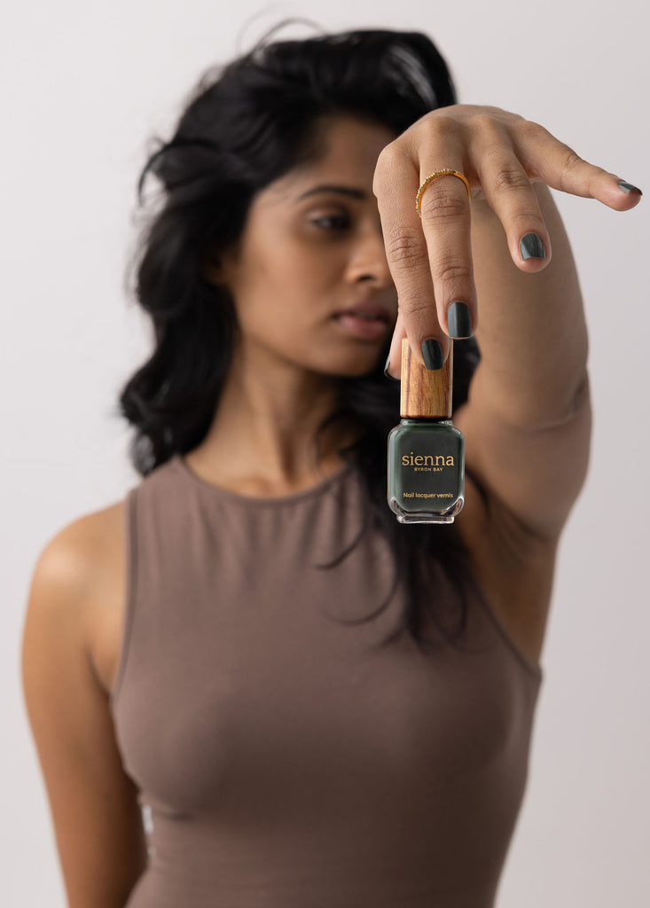 Woman with medium brown skin tone wearing Olivia dark green nail polish by Sienna Byron Bay