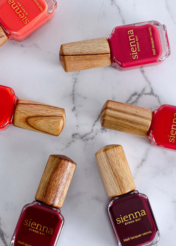 Sienna Byron Bay red nail polish bottles lying on marble surface