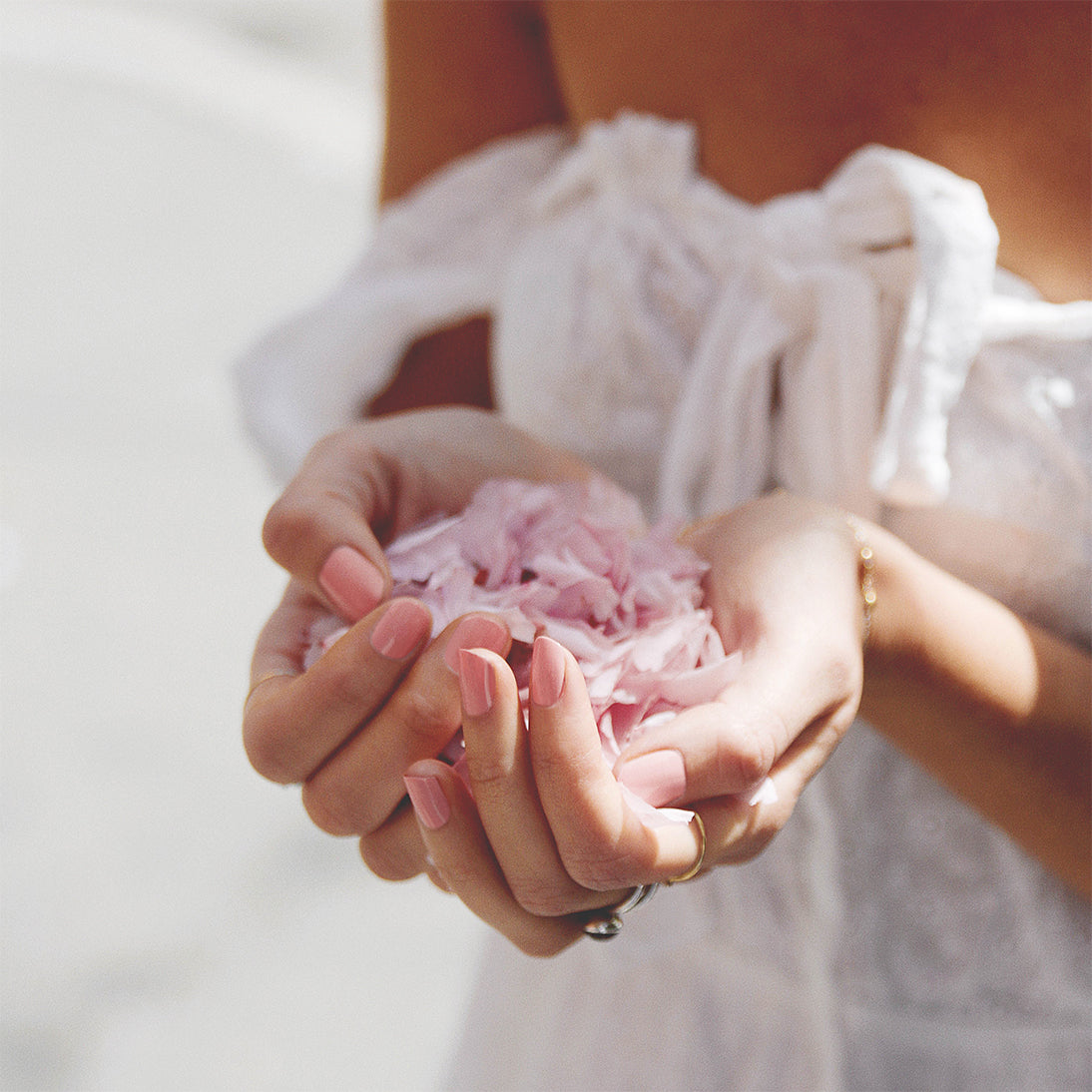 pink nail polish hands holding pink flower petals by sienna