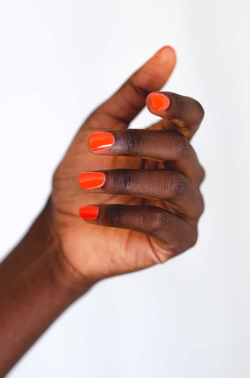 Tangerine orange nail polish hand swatch on dark skin tone by sienna