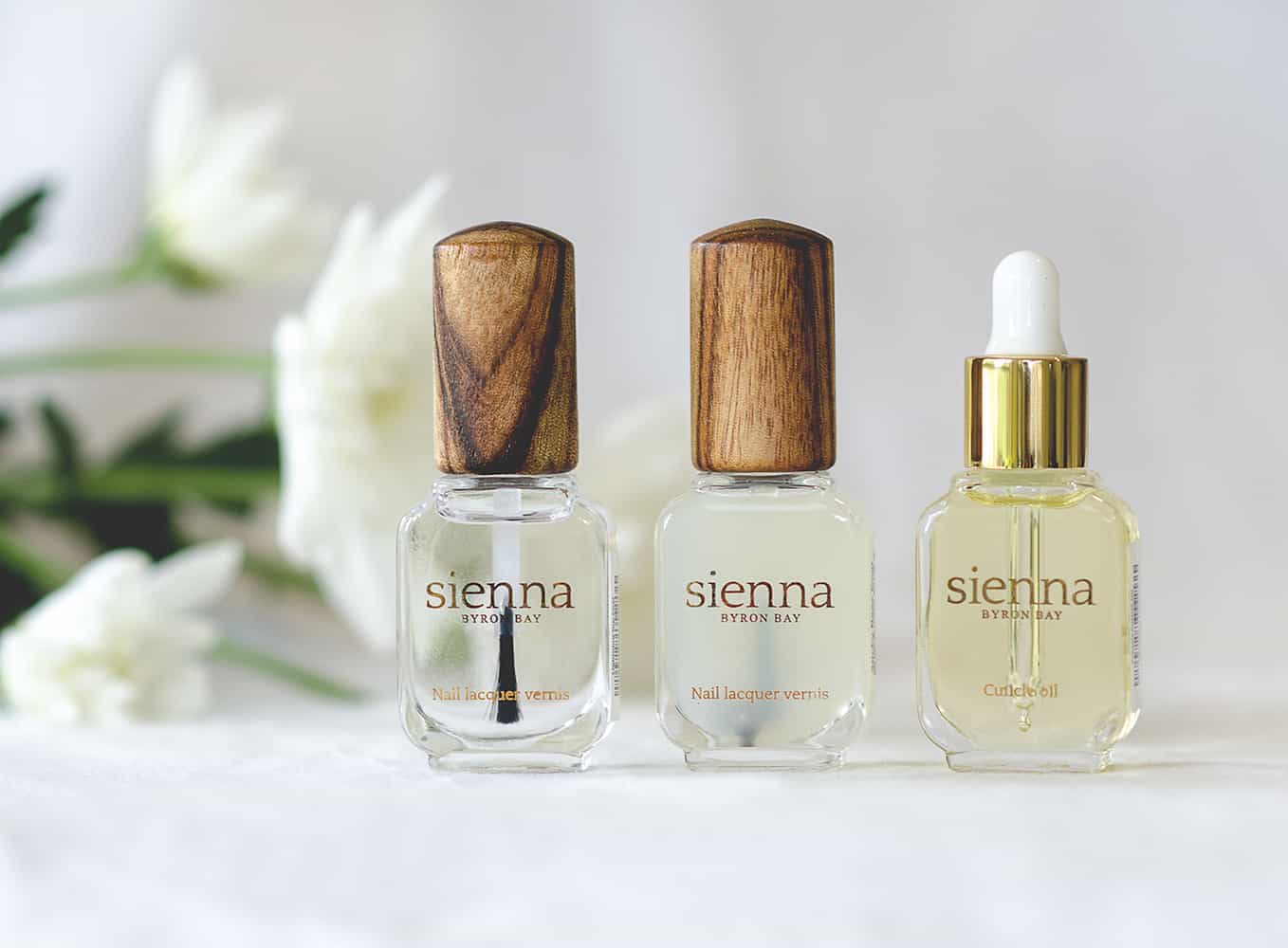 Lightning top coat, base coat and cuticle oil by sienna on white flowers background