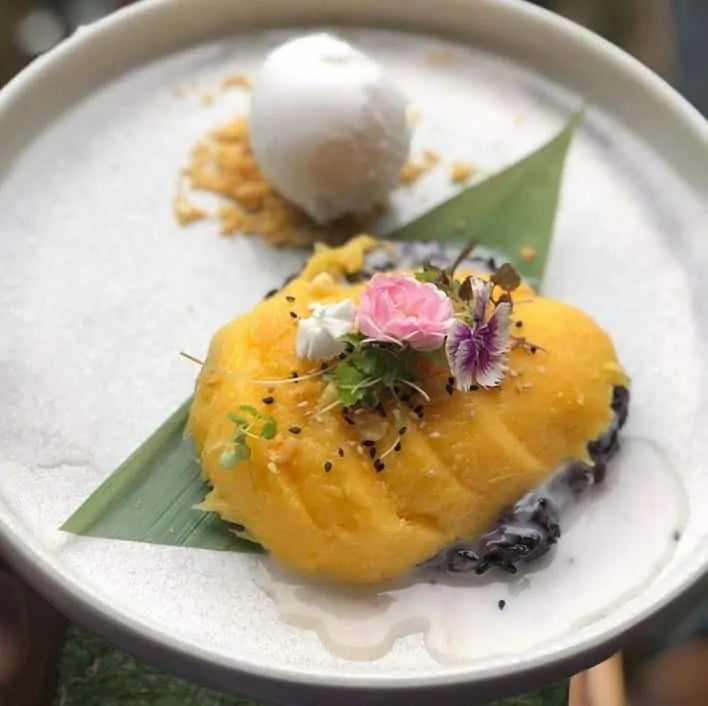 close view of mango slices dessert with comestible flowers from yullis restaurant in byron bay