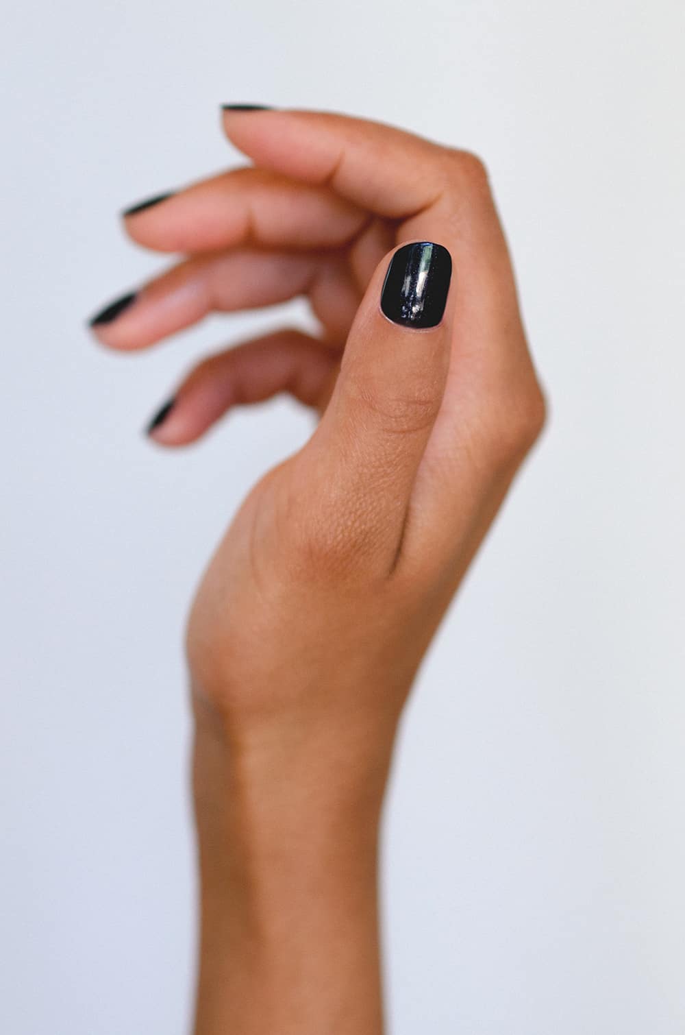 Black satin nail polish hand swatch on medium skin tone by sienna