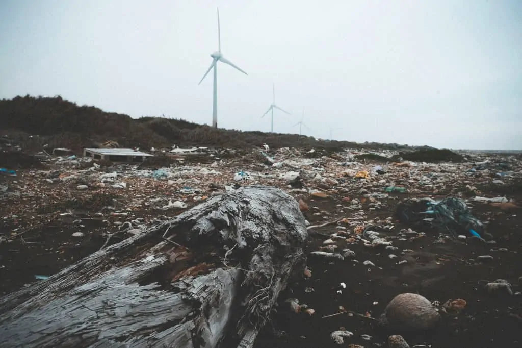 beach full of plastic waste with wind turbine in the background