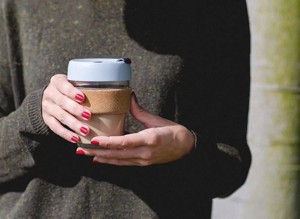 hands holding a reusable cup wearing bright red nail polish by sienna