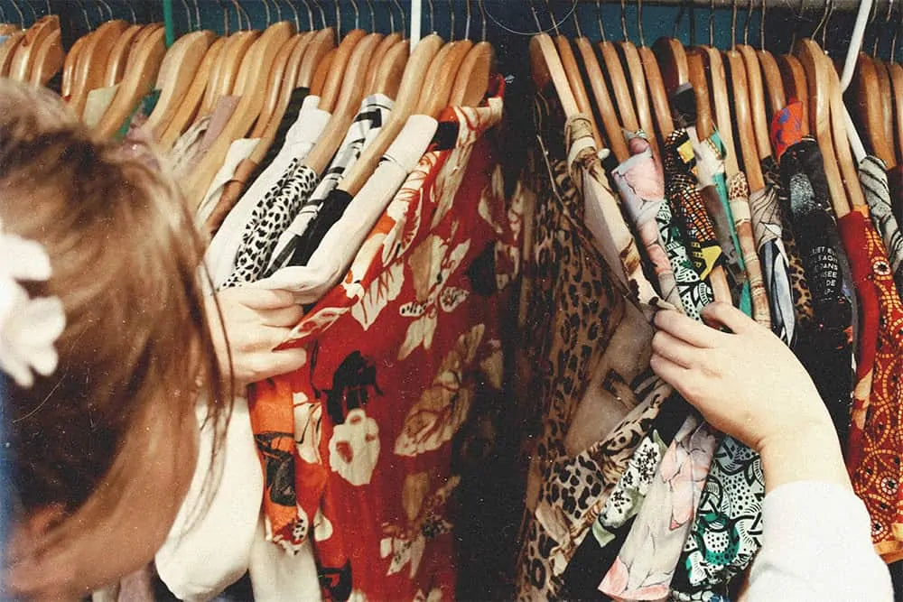 woman looking at shirts in a second hand clothes shop