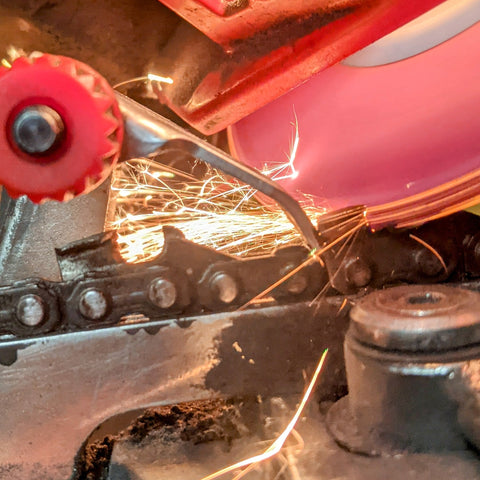 A chain saw chain being sharpened on an electric grinder