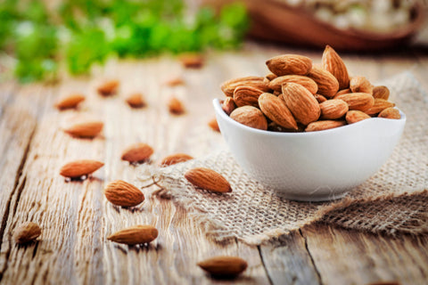 Almonds in white porcelain bowl on wooden table