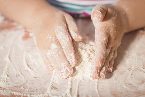 Little chef hands playing with flour