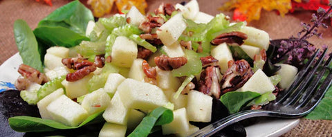 healthy salad with apples nuts and pecans shown plated with fork