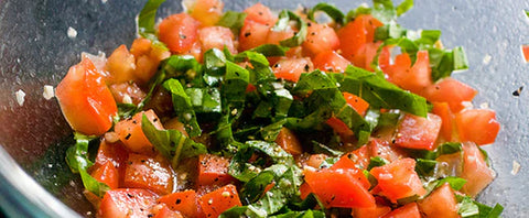 chopped tomato basil salad in a medium silver mixing bowl